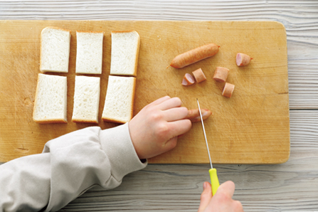 包丁でウインナーとパンを切る子ども