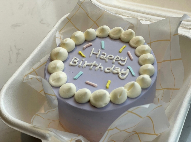 パープルのケーキにはHappy Birthdayの文字が。バタークリームでデコレーションされたケーキはセンイルケーキとして人気のお品。