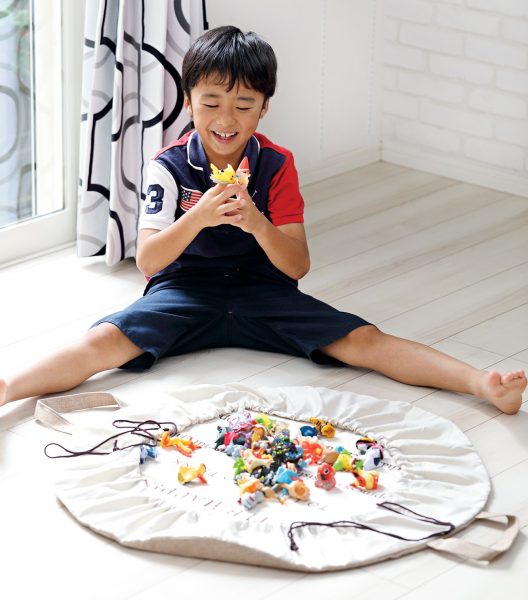 英語のロゴが入った３COINSのプレイマット風「片づけ巾着型マット」で遊ぶ男の子