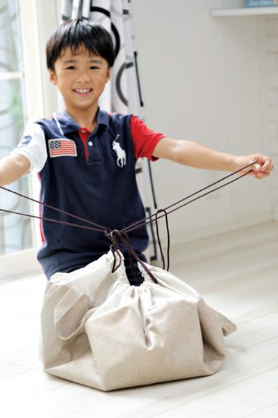 ３COINSのプレイマット風「片づけ巾着型マット」で遊んだ男の子が紐を結んでいるシーン