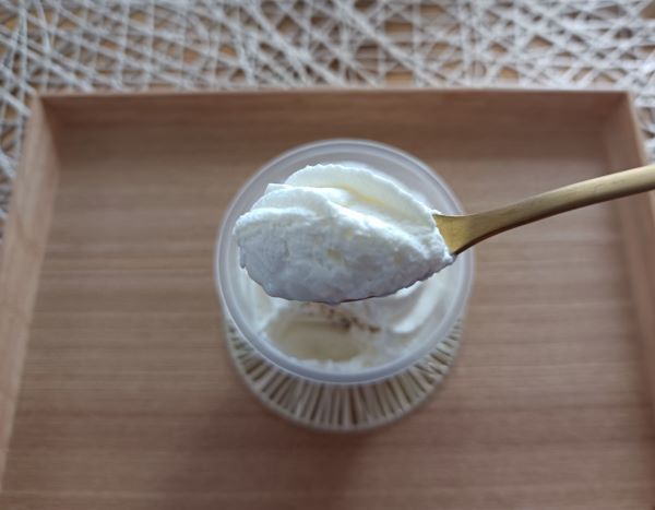 セブン-イレブン「ホイップクリームのミルクプリン」の上に乗っているホイップクリームをスプーンですくっている写真