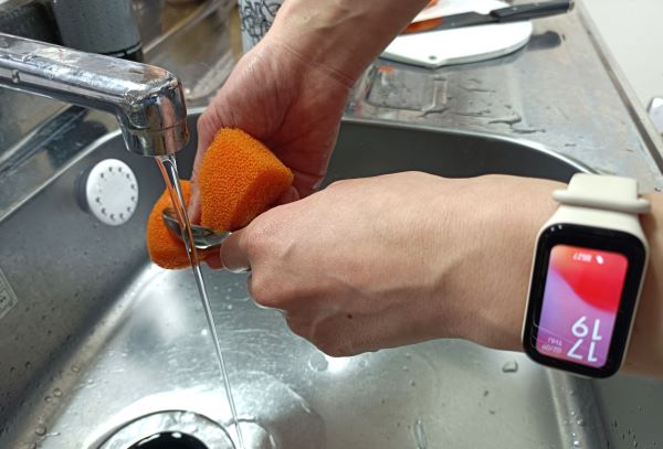 シャオミ「Redmi Smart Band 2」を着けながら食器洗いをする図（「Redmi Smart Band 2」の防水機能を説明するため）