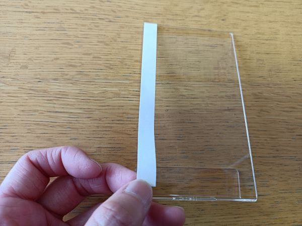 セリア「スマホにつけられるスマホスタンド」に付属の粘着テープを貼る図