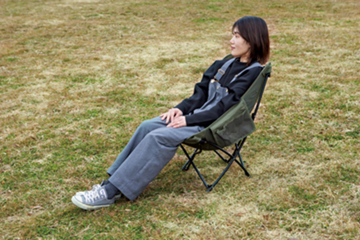 芝生に置かれたコールマンのアウトドアチェアに座る女性