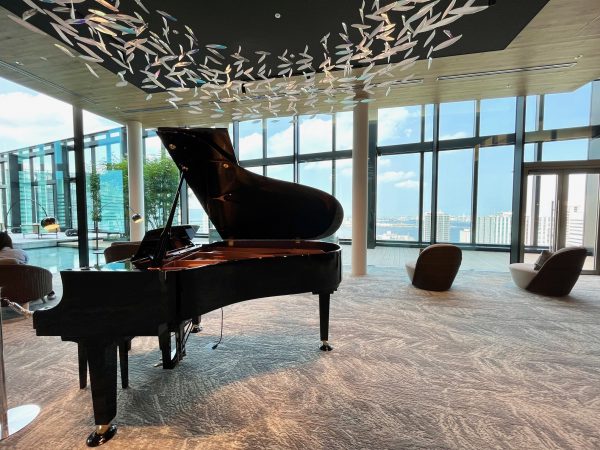 ホテルのロビーにグランドピアノと一人掛けイス、全面ガラス張りで景色が見える。