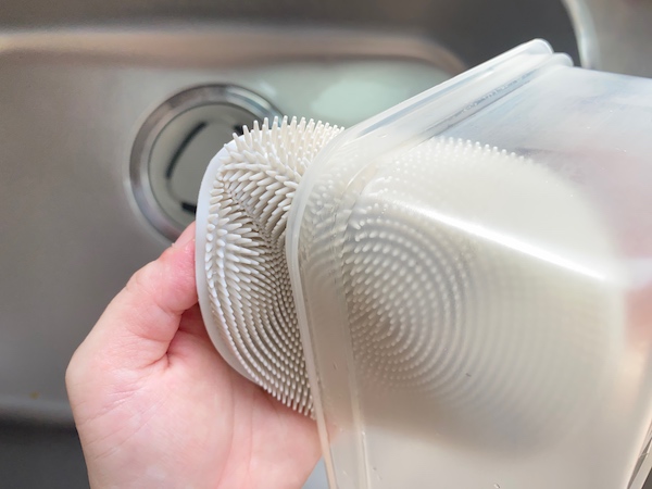 シリコーンスポンジ　サークル グレーでプラスチック製の保存容器を洗っている様子。