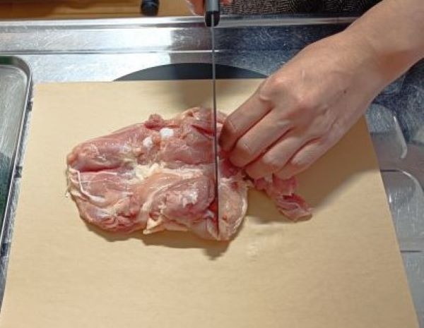 カインズ「すべりにくい紙のまな板シート」を敷いて鶏もも肉を切る図