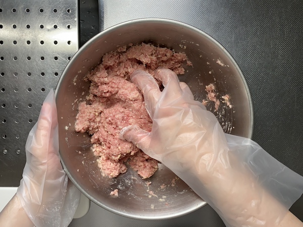 フィットしやすい使い切り手袋を手にはめて、ひき肉をこねている様子。